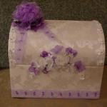 White Treasure Chest is covered in white bridal fabric. The top edge is trimmed with white bows and rhinestones.  The color of the bows, flower accessories and ribbons can be changed to match or compliment wedding colors.